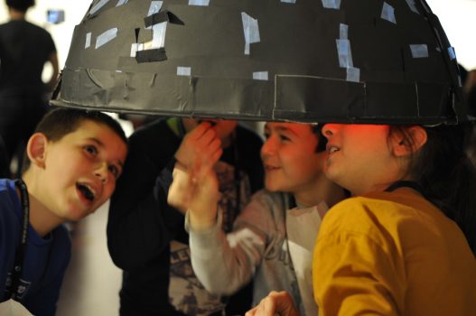 Kinder befinden sich unter einer der hohlen Halbschalen des Filterbubbel Workshops